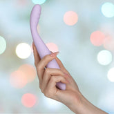 A hand holding the Svakom Cici 2 G-Spot Vibrator in pastel lilac, crafted from liquid silicone, against a blurred pastel background with circular bokeh lights.